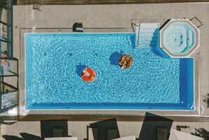 Una piscina al aire libre, sombrillas, sillones reclinables de piscina