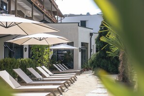Una piscina al aire libre, sombrillas, sillones reclinables de piscina