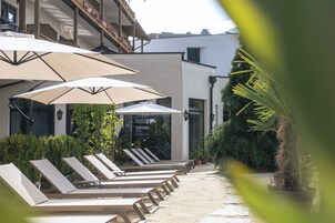 Una piscina al aire libre, sombrillas, sillones reclinables de piscina