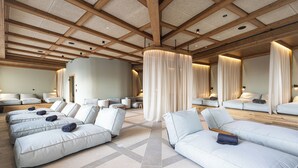 A spa room with multiple massage beds, a large curtain, and a wooden ceiling.
