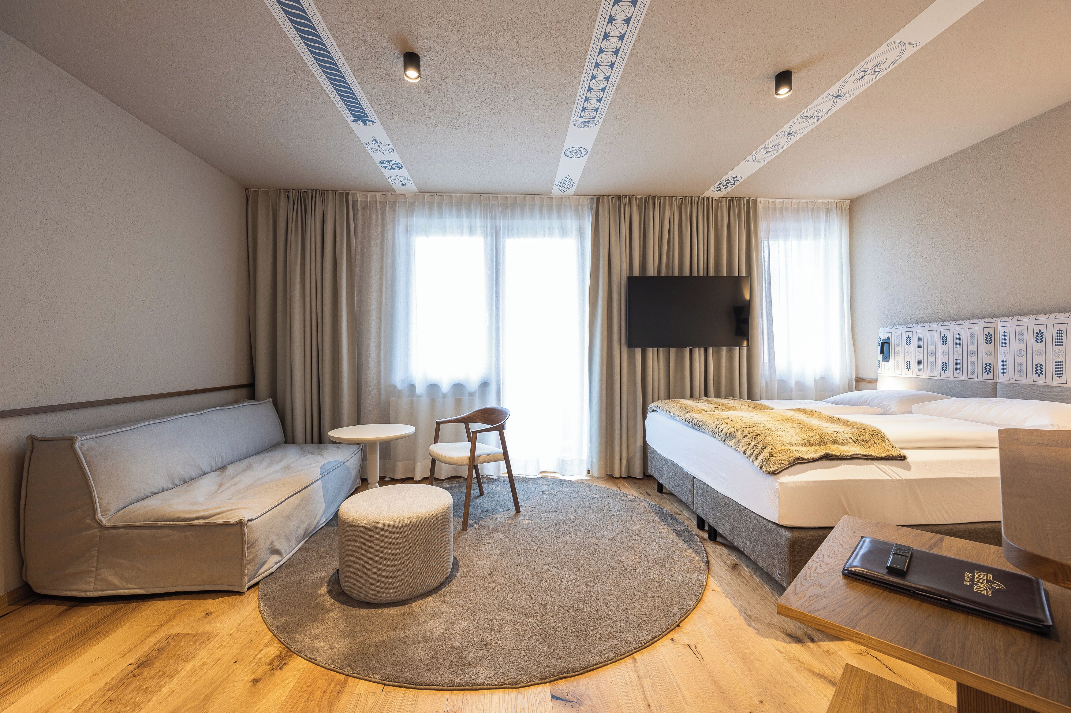 Een hotelkamer met een bed, een slaapbank, een tafeltje, een stoel en een tv aan de muur.