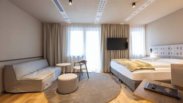 Een hotelkamer met een bed, een slaapbank, een tafeltje, een stoel en een tv aan de muur.
