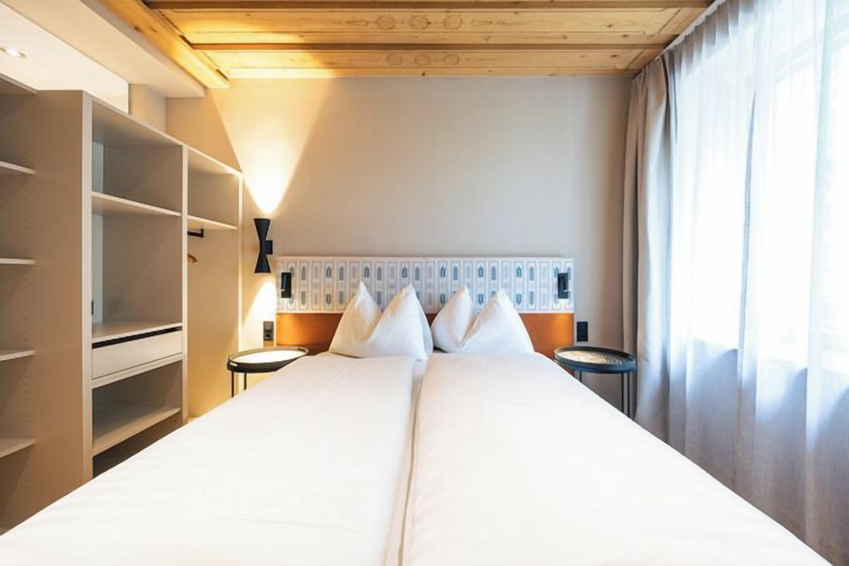 Ein Hotelzimmer mit einem großen Bett, einem Kleiderschrank, einem Nachttisch und einer Lampe.