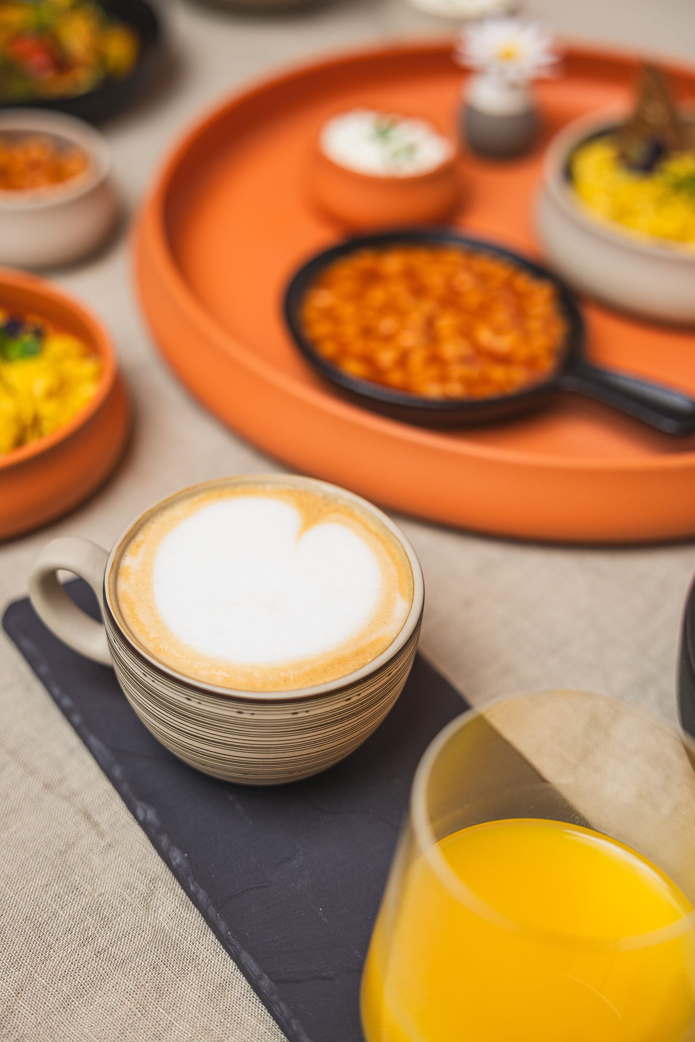 A table with a coffee cup, a glass of orange juice, and various dishes.