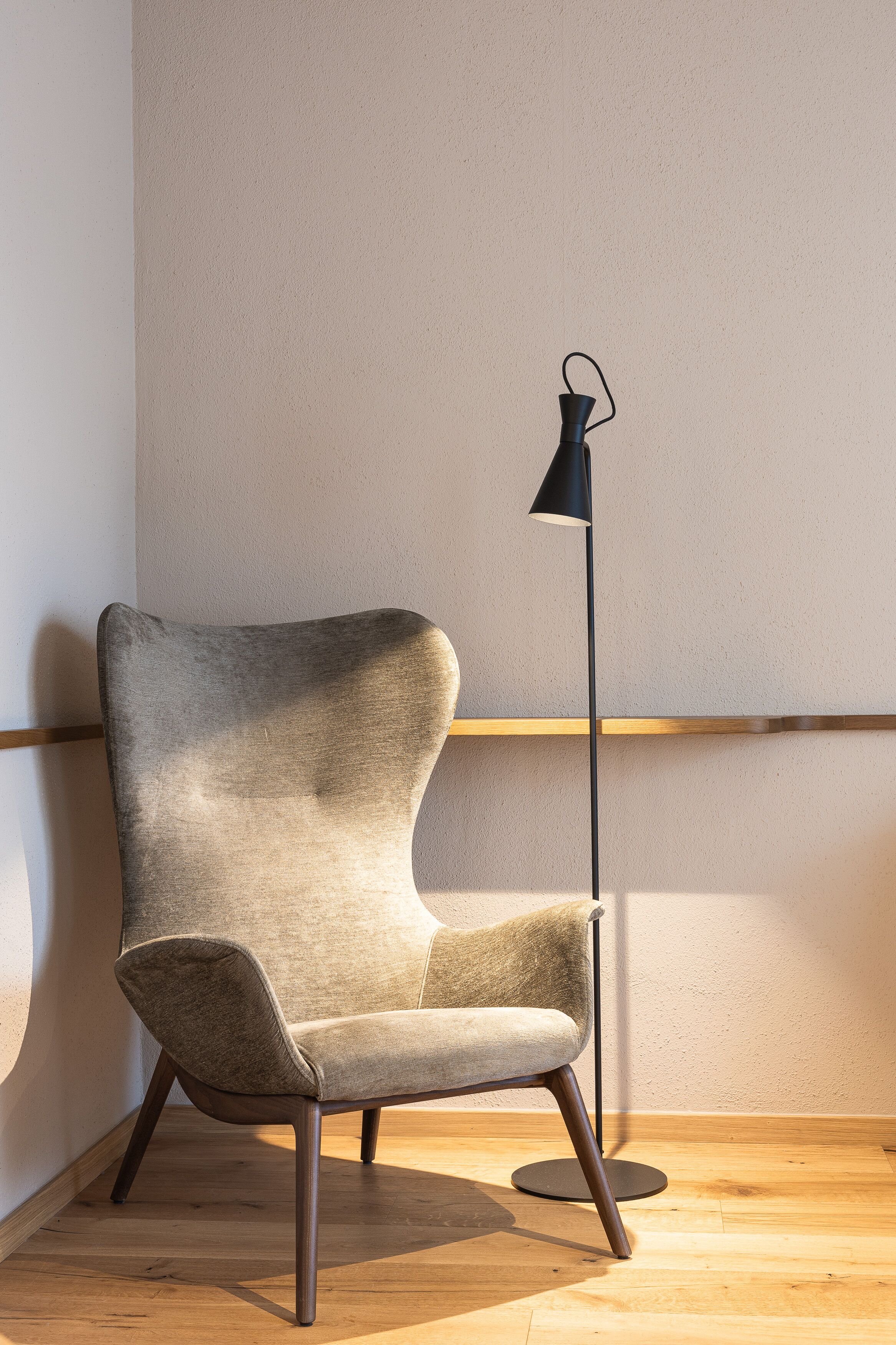 Een stoel met een hoge rugleuning en een vloerlamp ernaast.