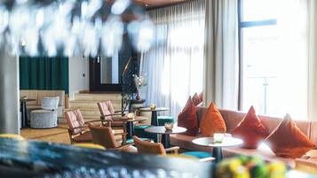 Um lobby de hotel moderno com sofás, cadeiras, mesas e uma escadaria.