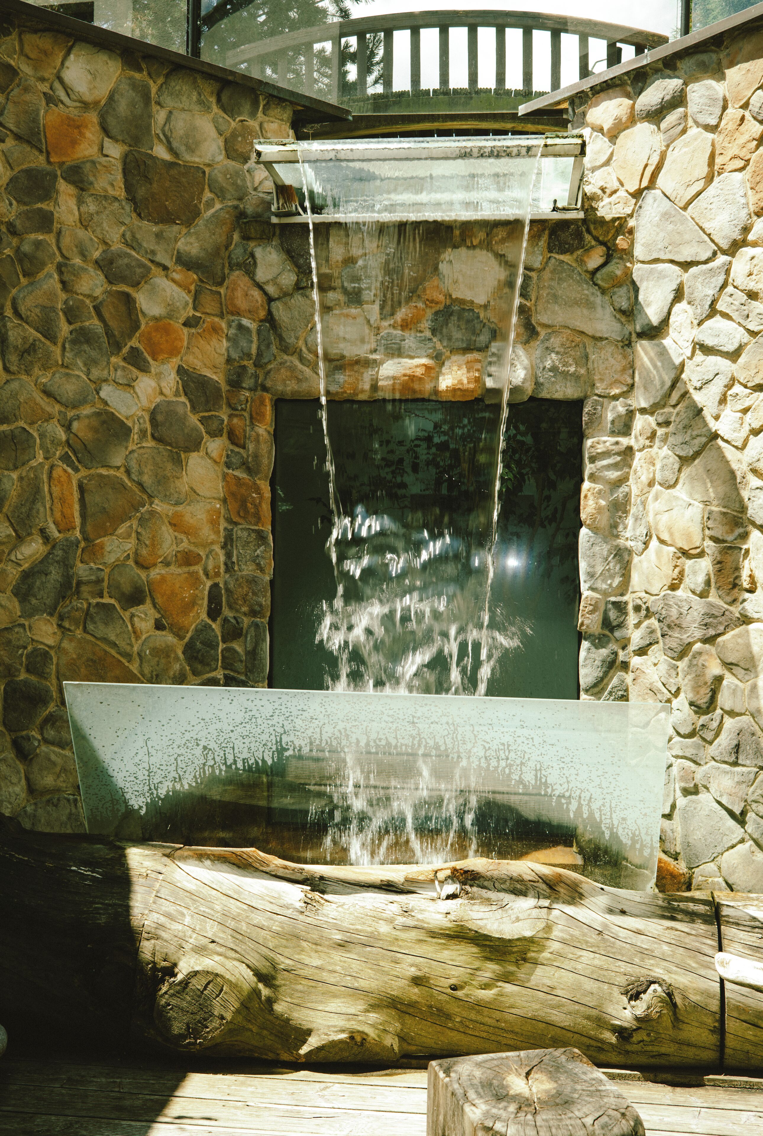 A stone wall with a water feature, including a waterfall and a pool.