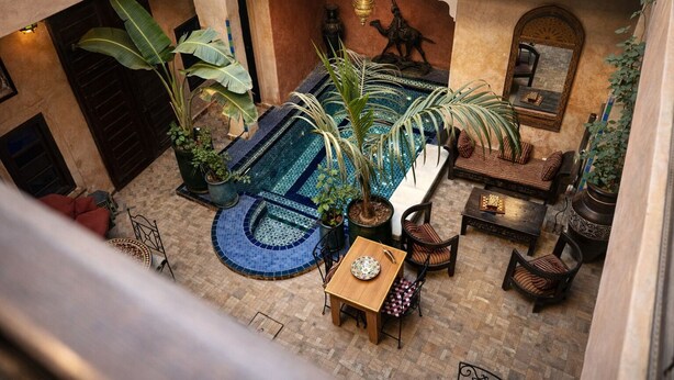 Un patio con piscina, zona de estar y plantas en macetas.