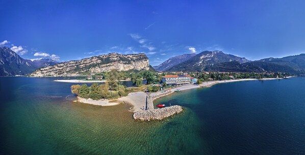 Eine Küstenstadt mit einem markanten Berg im Hintergrund, klarem, blauem Wasser und einer kleinen Insel mit felsiger Küste.