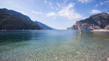 A clear lake with rocky shores and mountains in the background.
