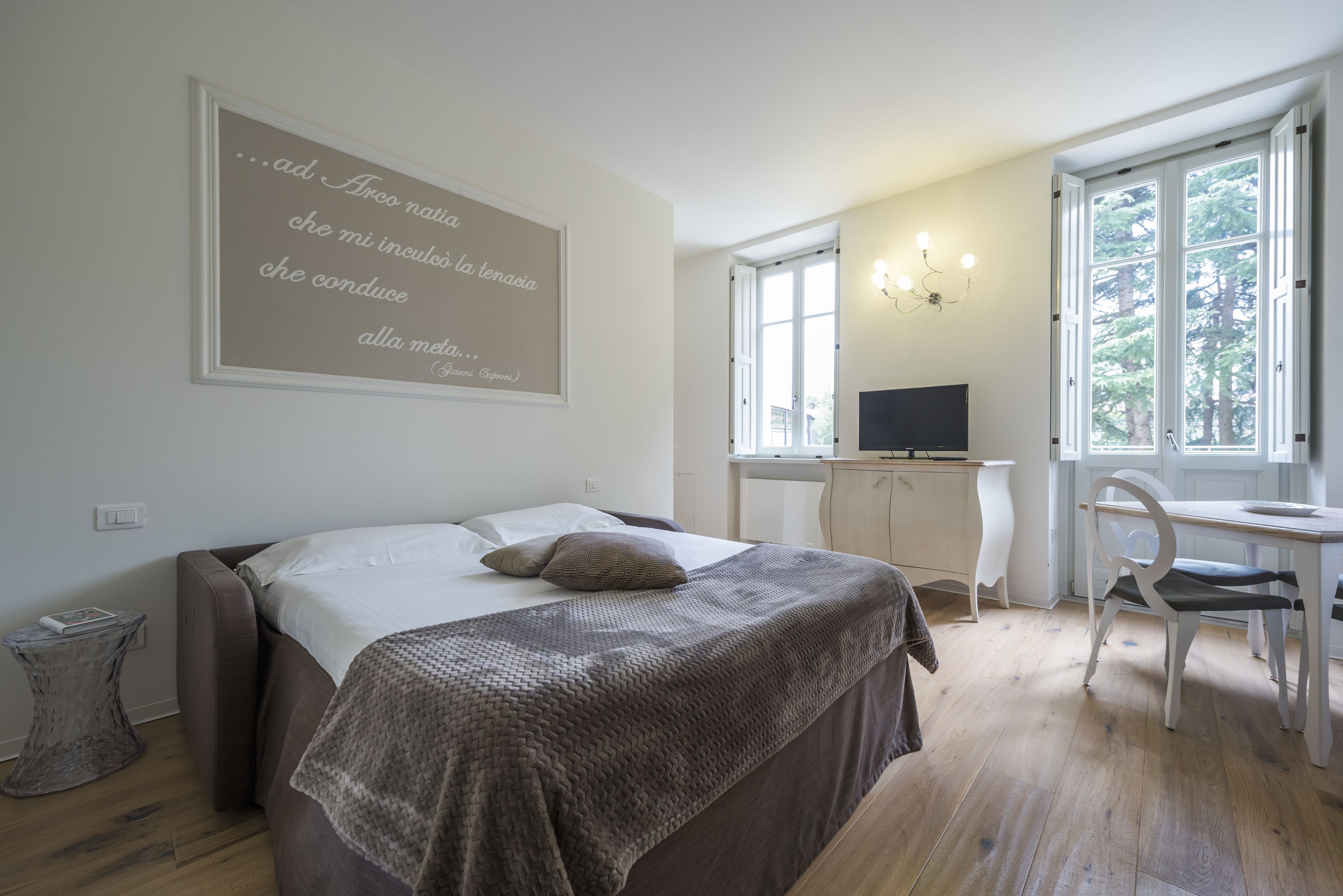 Een slaapkamer met een bed, een bureau, een stoel en een groot raam.