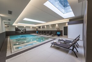 Una piscina techada, sillones reclinables de piscina
