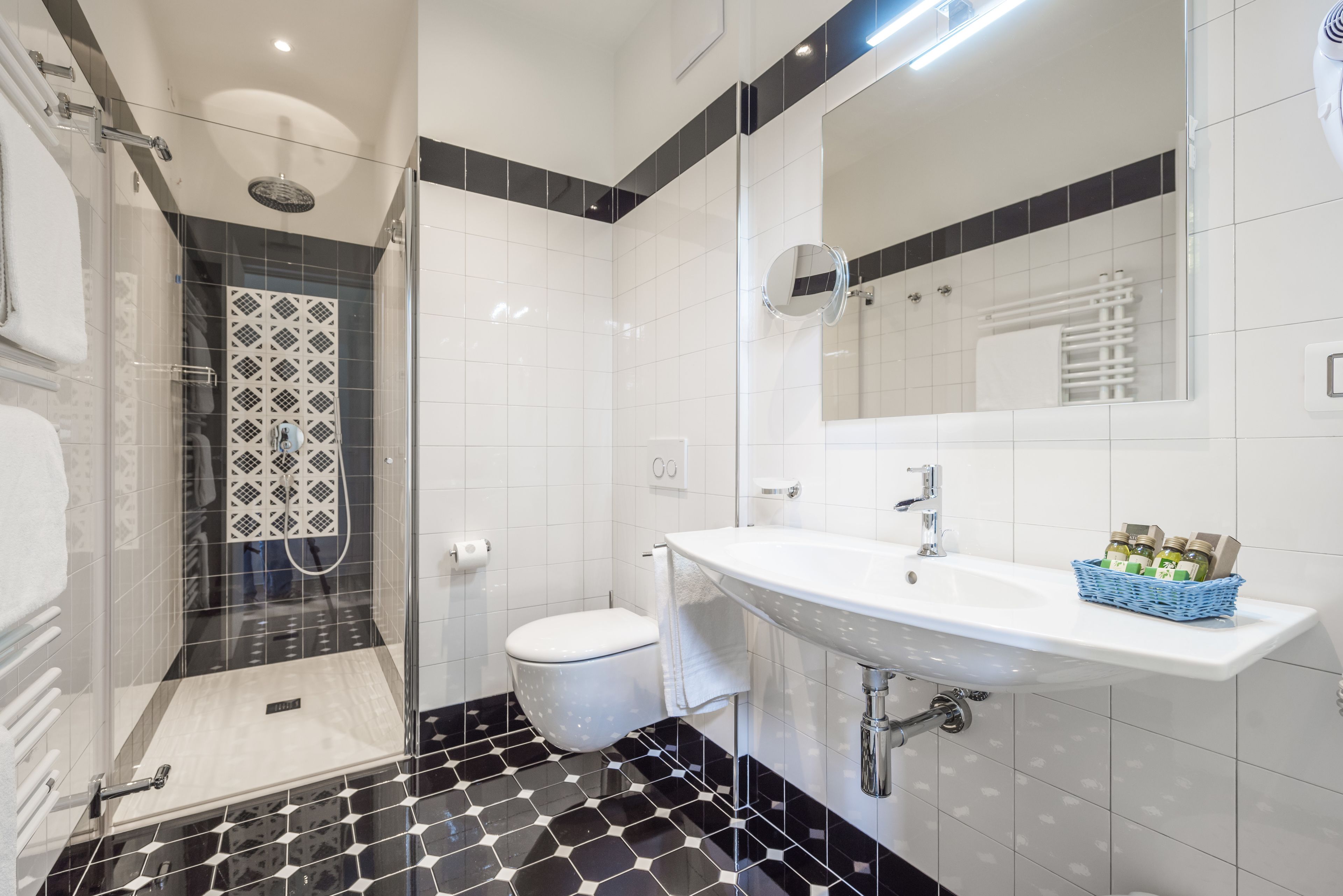 Un baño moderno con ducha de vidrio, lavamanos blanco y un espejo grande.