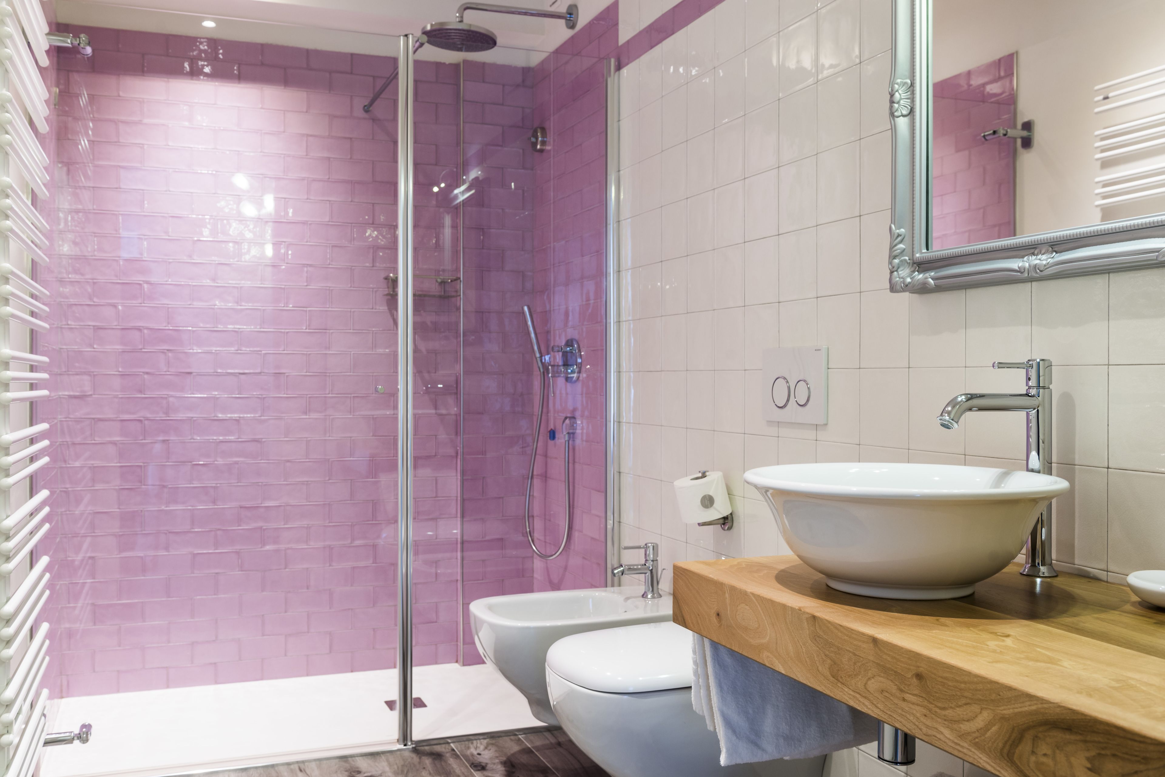 Ein modernes Badezimmer mit einer gläsernen Duschkabine, einem weißen Waschbecken und einem Holzbadezimmer-Möbel.