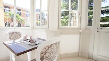 Una habitación de esquina con una mesa de comedor para dos personas, ventanas amplias y paredes blancas.