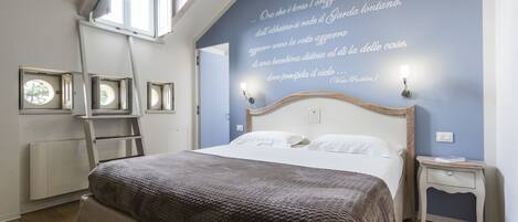A bedroom with a bed, a ladder, a wall with a quote, and a small bedside table.