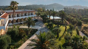 A hotel with a pool, palm trees, and a mountainous backdrop. - Paradise Hotel Corfu (Corfu)