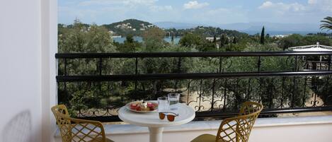 A balcony with a table and chairs, overlooking a scenic view of a lake and hills.
