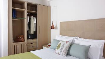 Una habitación de hotel con cama, armario, mesita de noche y una lámpara de pared.