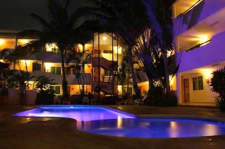 Una piscina al aire libre, sombrillas, sillones reclinables de piscina