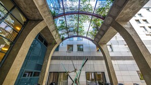 A modern atrium with a glass ceiling, stone columns, and a central water feature. - Continental Hotel Budapest (Budapest)