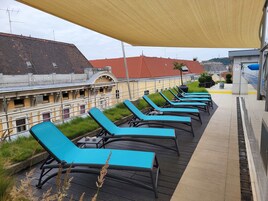 Terraza en la azotea con sillones azules y un toldo amarillo.
