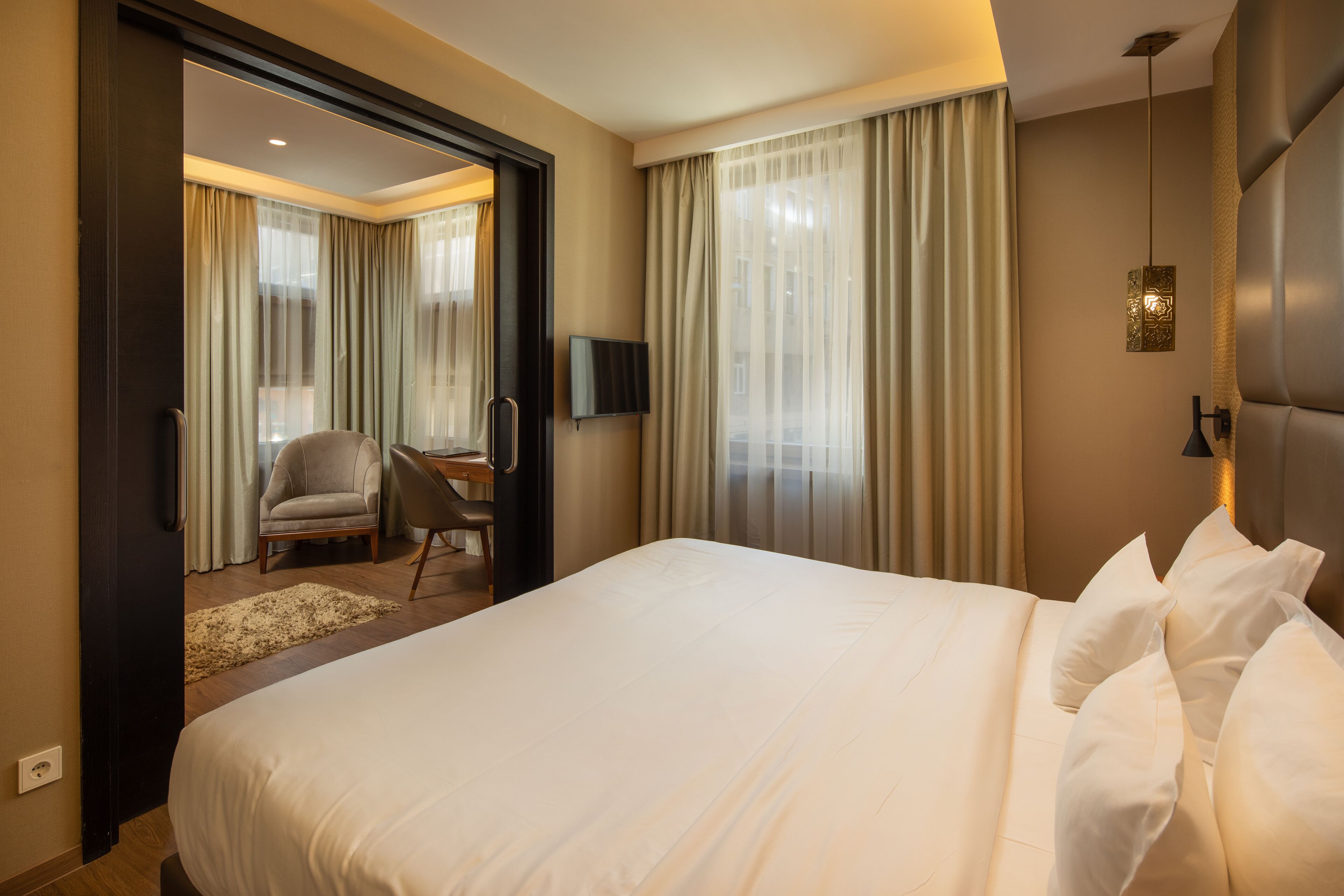 Una habitación de hotel con una cama grande, un escritorio, una silla y un televisor.