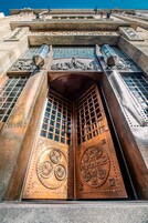 Μια μεγάλη, περίτεχνη μεταλλική πόρτα με περίπλοκα σχέδια και ένα πλέγμα από μικρά παράθυρα.