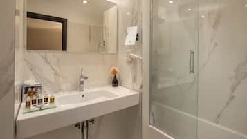 Une salle de bain moderne avec un lavabo en marbre, une cabine de douche en verre et un grand miroir.