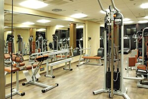 Ένα γυμναστήριο με διάφορα όργανα γυμναστικής, καθρέφτες και ξύλινο δάπεδο.