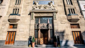 A building facade with a central entrance, flanked by two potted plants, and a sign above the entrance. - Continental Hotel Budapest (Budapest)