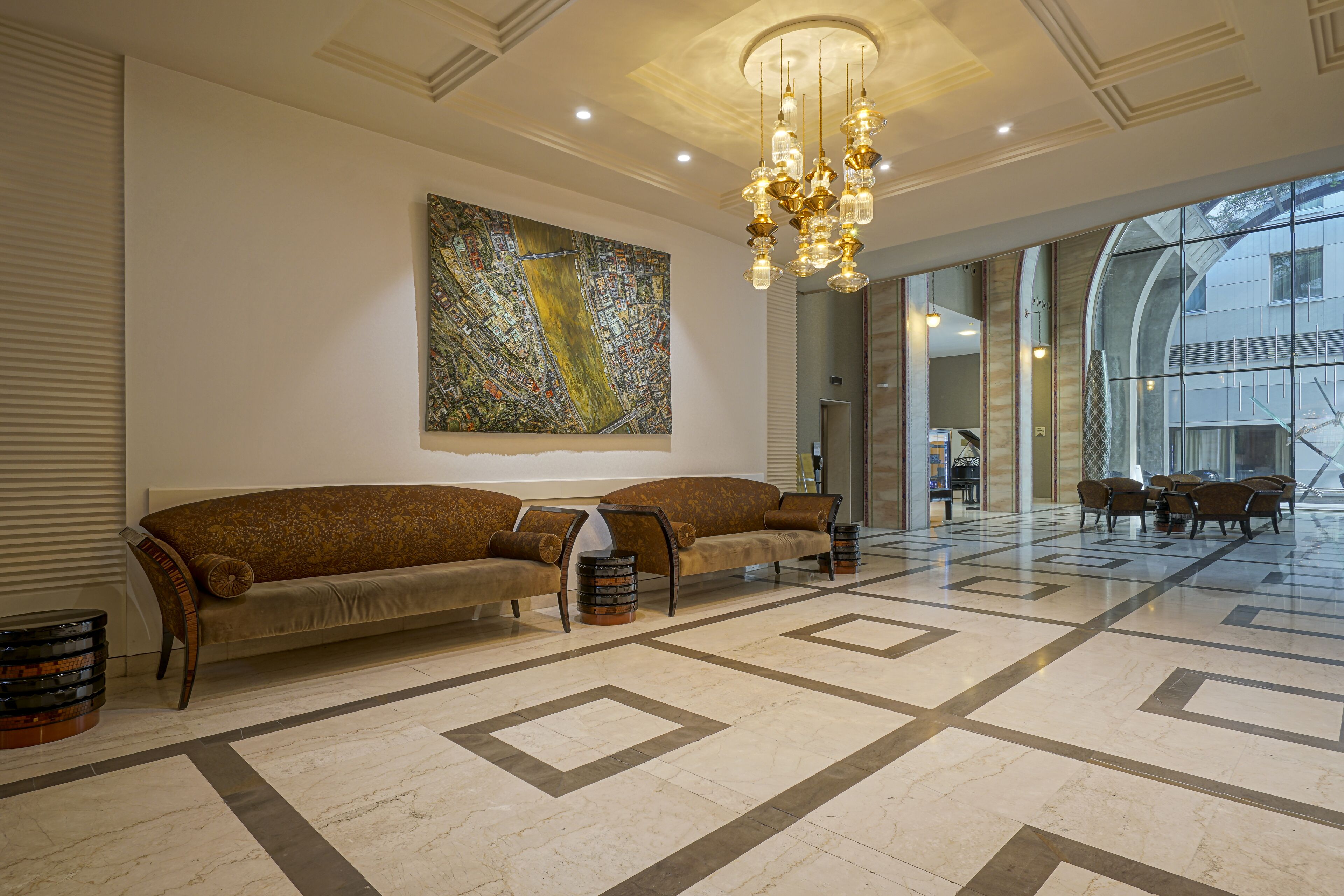 Un hall d’entrée spacieux, agrémenté d’un grand tableau abstrait, d’un lustre moderne et d’un espace détente avec des canapés et une table basse.