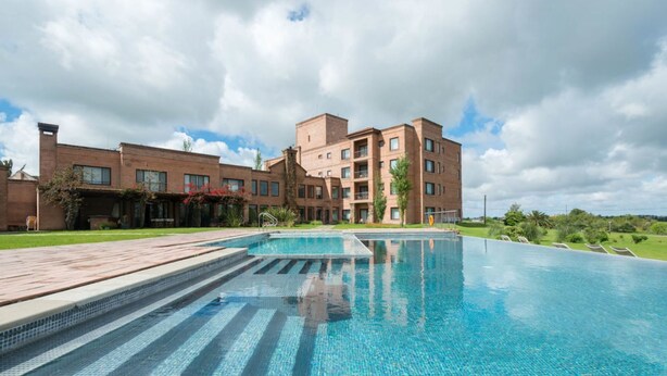 Un hotel moderno con piscina, edificios de ladrillo y césped bien cuidado.
