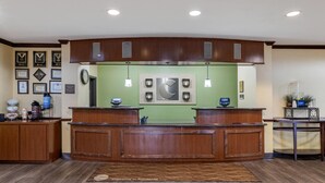 A reception area with a wooden reception desk, framed certificates on the wall, and a clock. - Comfort Inn & Suites Navasota (Navasota)