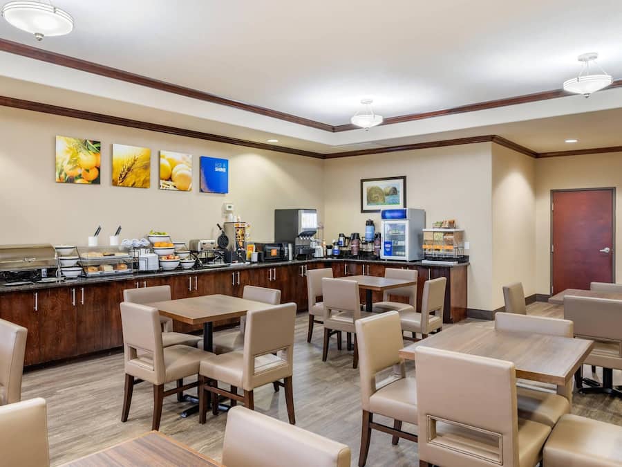Zona de desayuno de hotel con bufé, asientos y obras de arte en las paredes.