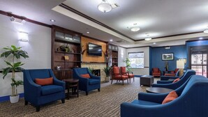 A hotel lobby with blue armchairs, a flat-screen TV, and a large window. - Comfort Inn & Suites Navasota (Navasota)