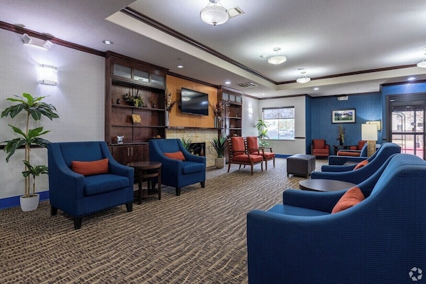 Un hall d’hôtel avec des fauteuils bleus, un téléviseur à écran plat et une grande fenêtre.
