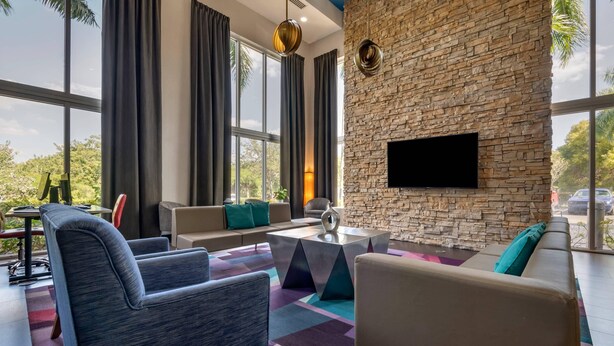 Una sala de estar moderna con pared de piedra, ventanas amplias y televisor de pantalla plana.