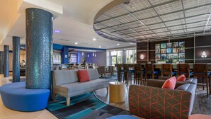 Un moderno vestíbulo de hotel con zona de bar, asientos y vistas al exterior.