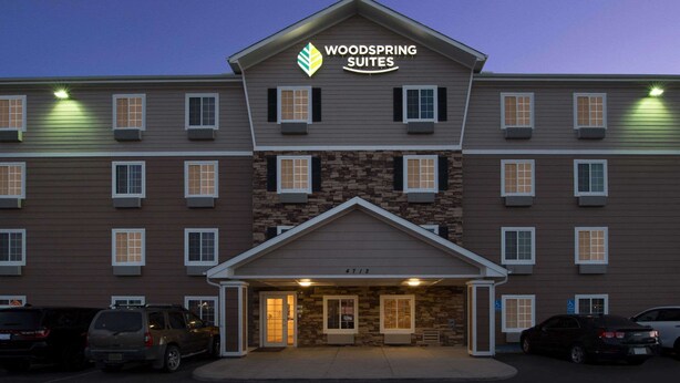 A multi-story hotel with a stone facade and a sign reading "Woodspring Suites". - WoodSpring Suites Midland (Midland)