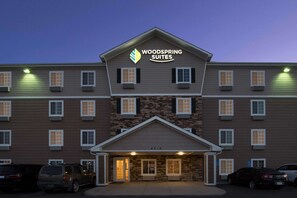 A multi-story hotel with a stone facade and a sign reading "Woodspring Suites". - WoodSpring Suites Midland (Midland)