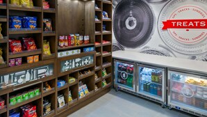 Una sección de aperitivos y dulces con estantes llenos de papas fritas, refrescos y productos refrigerados.