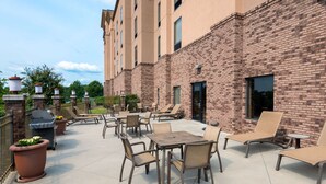 Un patio al aire libre con mobiliario, una parrilla y un edificio de ladrillo.