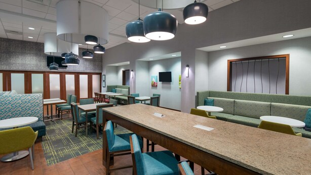 Un restaurante moderno con una mesa común alargada, cabinas y mesas individuales.