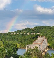 Un puente con un arcoíris, rodeado de exuberante vegetación y casas.