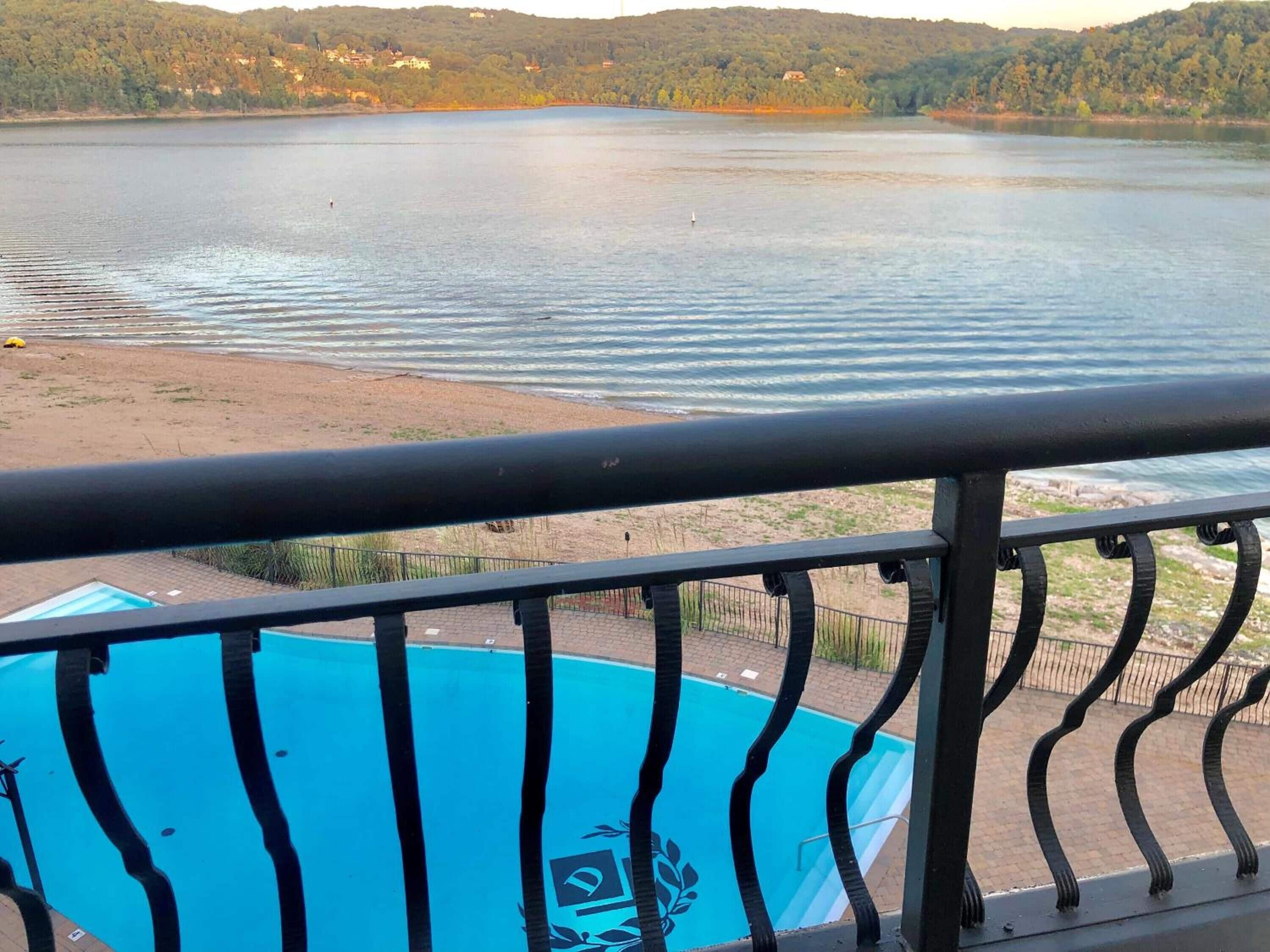 A pool with a view of a lake and distant hills.