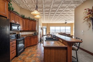 Una cocina con armarios de madera, un refrigerador negro, un microondas y una isla grande con un lavamanos.