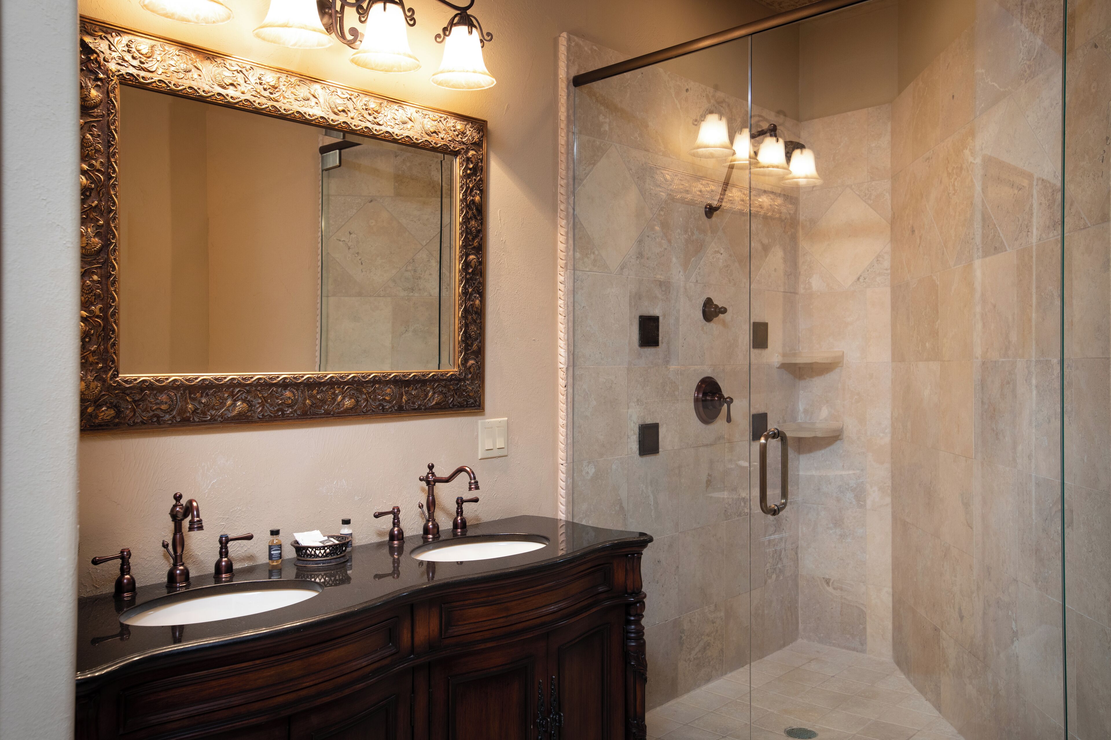 A bathroom with two sinks, a large mirror, and a glass-enclosed shower.