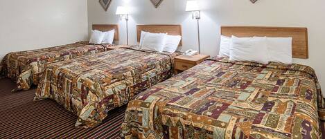 A hotel room with two beds, each with a patterned bedspread, wooden headboards, and bedside lamps.