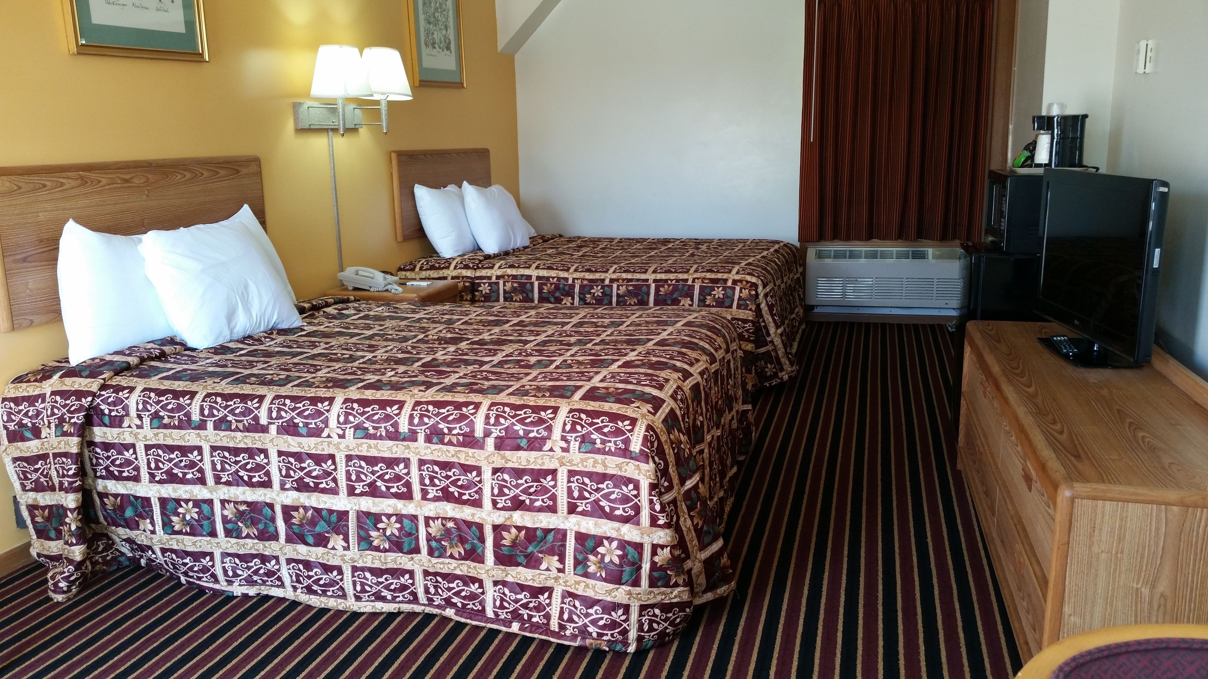 A hotel room with two beds, a desk, a TV, and a coffee machine.